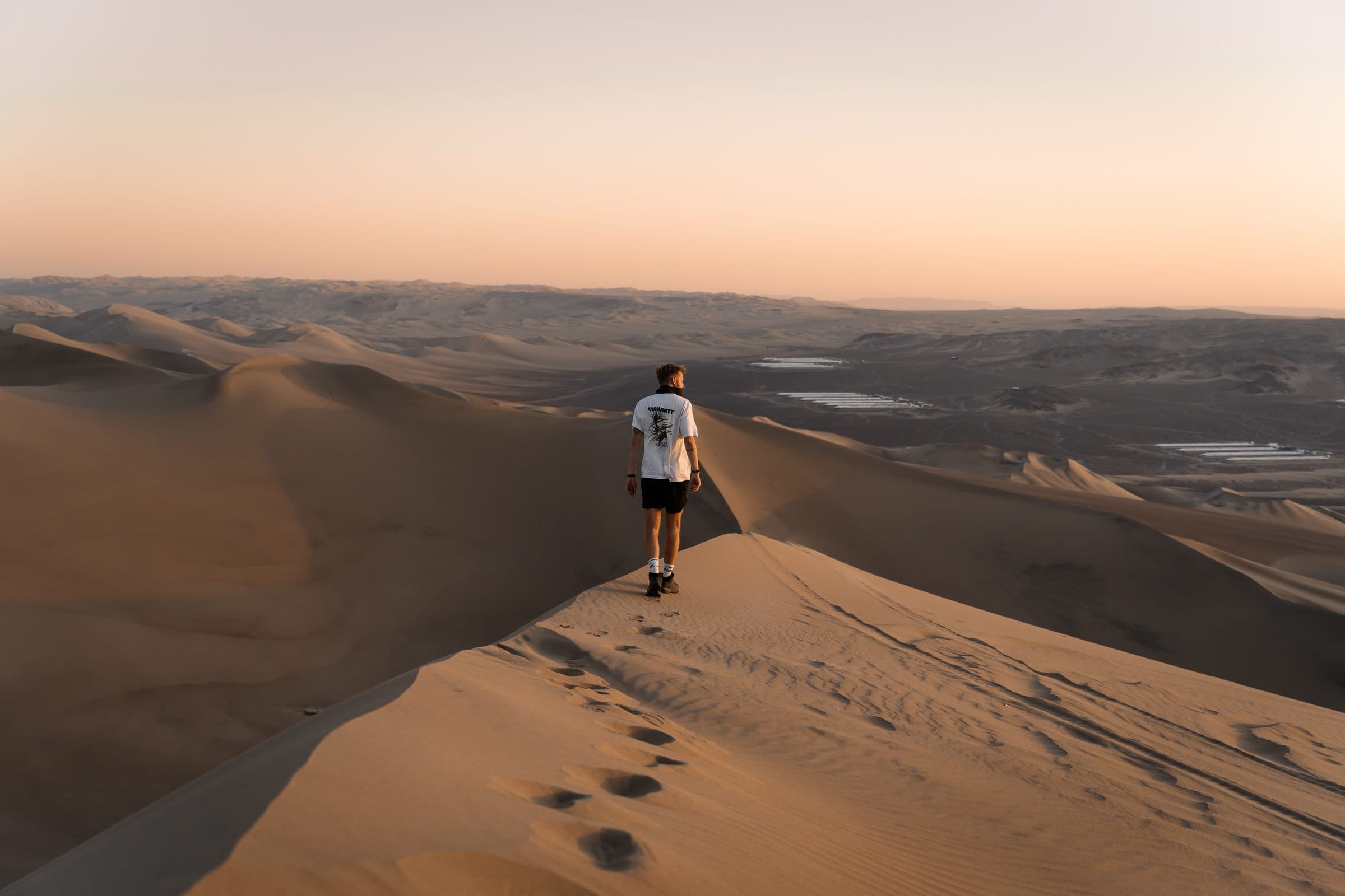 Guus Alderden walking along the crest of a sand dune at sunset, footprints trailing behind him